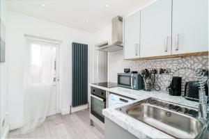 a kitchen with a sink and a microwave at Modern 2 bed apartment close to Westfield Stratford mall with garden in London
