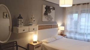 um quarto com uma cama branca e uma janela em Apartamento a 30 metros de la playa em San Vicente de la Barquera