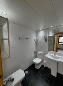 ein Badezimmer mit einem WC, einem Waschbecken und einem Spiegel in der Unterkunft AT home Santo Domingo in Guadalajara
