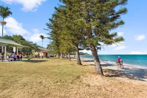 a person riding a bike on the beach at Beach Pad Private Town house Sea Views Dual living 5 Beds in Redcliffe