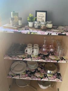 un estante de flores con platos y otros artículos. en Die Kliphuisies 2, en Oudtshoorn