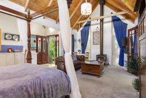 una camera da letto con un letto e un soggiorno di Bluebell Cottage Gembrook - Heated Spa & Wood Fireplace a Gembrook