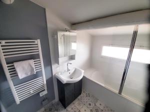 ein weißes Bad mit einem Waschbecken und einer Dusche in der Unterkunft The Cosy House in Périgny
