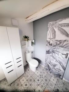 baño con aseo y una pintura en la pared en The Cosy House, en Périgny