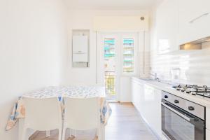 een witte keuken met een tafel en stoelen bij Appartamento vista mare di Marco in Spotorno