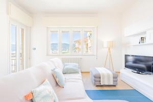 a living room with a white couch and a tv at Appartamento vista mare di Marco in Spotorno