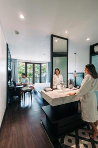 a woman standing in a bathroom with a large mirror at De An Hotel in Hoi An