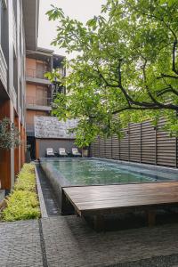 a swimming pool with a wooden bench next to a building at Hotel Loy Chiang Mai in Chiang Mai