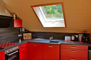 een rode keuken met een wastafel en een raam bij Ferienwohnung Preisinger in Gammertingen