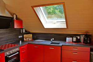 a red kitchen with a sink and a window at Ferienwohnung Preisinger in Gammertingen