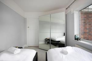 a white room with two beds and a mirror at Hömli-Cosy-Spacious-GardenView in Sileby