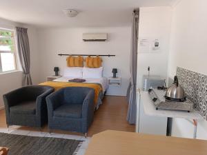 a bedroom with a bed and two chairs at NoulAnouk's Corner - Peaceful Studio in Cape Town