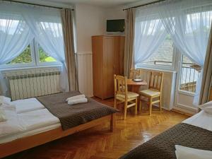 a bedroom with two beds and a table and two windows at Noclegi U Reni in Białka Tatrzańska
