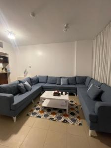 a living room with a blue couch and a coffee table at مارينا KAEC in King Abdullah Economic City