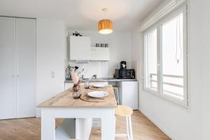 a white kitchen with a wooden table and chairs at Le Havre du Bonheur in Saint-Denis