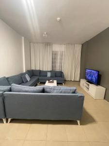 een woonkamer met een blauwe bank en een tv bij مارينا KAEC in King Abdullah Economic City