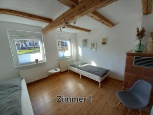 een slaapkamer met een bed en een stoel en 2 ramen bij Pension Kleinschmidt in Urbach