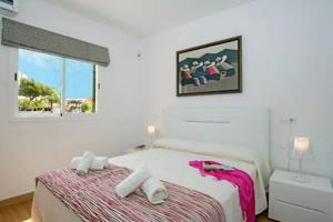 a white bedroom with a bed and a window at Oleanda in Port d'Alcudia