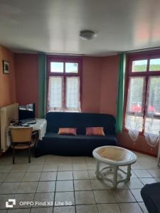 a living room with a blue couch and a table at Appart la Percep in La Tour-dʼAuvergne