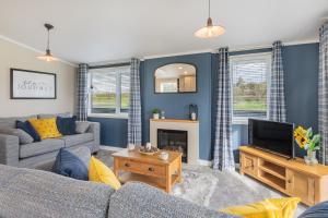 a living room with a couch and a tv at Oak Tree Timber Holiday Lodge in Bassenthwaite