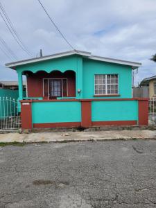 une maison verte et rouge avec une clôture dans l'établissement Kensington Oval- 2 bed 1 Bath, à Bridgetown