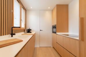 een keuken met witte werkbladen en houten kasten bij Bright & elegant stand alone chalet - 8 ppl - Vois Le Mont in Les Gets +13 foto's