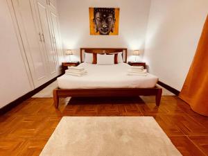 a bedroom with a bed with white sheets and two lamps at Hollywood villa in Campanário