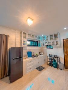 Isabela Province Staycation House في Cordon: مطبخ فيه دواليب بيضاء وثلاجة سوداء