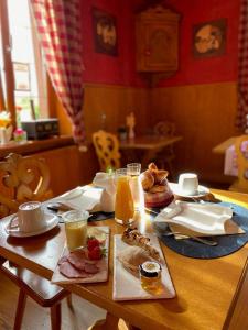 Le Rosenmeer - Hotel Restaurant, au coeur de la route des vins d'Alsace في Rosheim: طاولة خشبية عليها طعام ومشروبات للإفطار