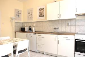 a kitchen with white cabinets and a table at Panoráma Apartman in Cegléd