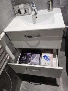 an open drawer under a white sink in a bathroom at Appart avec jardin proche Paris in Aubervilliers