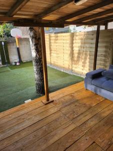 un portico con un divano blu su un pavimento in legno di Appart avec jardin proche Paris ad Aubervilliers