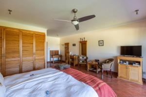 a bedroom with a bed and a tv and a table at Gästehaus Pinkepank in Plettenberg Bay