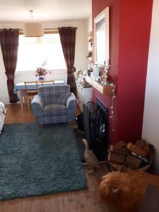 uma sala de estar com um sofá, uma cadeira e uma lareira em Cosy 2 bedroom house on the edge of Balloch em Balloch