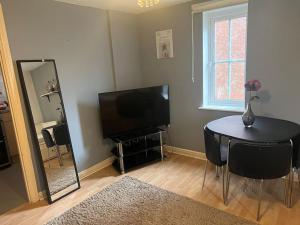 een woonkamer met een tafel, een televisie en een spiegel bij Quiet and peaceful in Hatfield