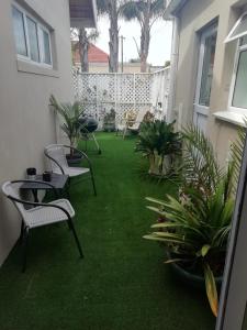 a patio with chairs and plants in a yard at The Palm in Cape Town