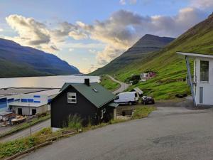 uma casa preta com uma carrinha branca estacionada ao lado de uma montanha em Amazing Sea and Mountain View em Klaksvík