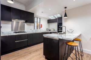a kitchen with black cabinets and white counter tops at Berelands House - Donnini Apartments in Prestwick