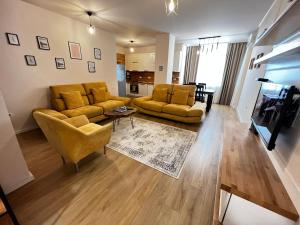 uma sala de estar com dois sofás amarelos e uma mesa em City Centre Apartments em Tirana