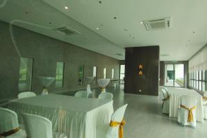 a dining room with white chairs and a table at Sunway Onsen Suites - Theme Park Tambun Ipoh by Ryokan Management in Tambun