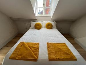 a white bed with two yellow pillows and a window at Henley Bolt Hole in Henley on Thames