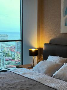 a bedroom with a bed and a large window at Season Suite Apart-Hotel in Batumi