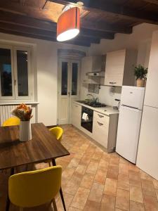 a kitchen with a wooden table and yellow chairs at FEEL - Piazza Pontida Balcony Apartment in Bergamo