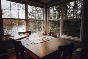 a wooden table in a room with windows at Chalet plein air in Saint-Raymond