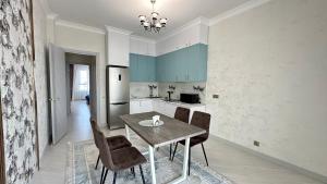 eine Küche mit einem Tisch und Stühlen sowie einem Kühlschrank in der Unterkunft 2х комнатные апартаменты 12-106 in Almaty