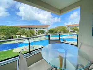 a balcony with a glass table and a view of a swimming pool at Paraíso na terra - Carneiros Beach Resort in Tamandaré