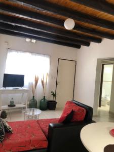 a living room with a red couch and a tv at AeroSuites in Las Heras