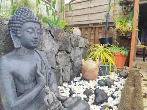une statue d'un buddha assise dans un jardin rocheux dans l'établissement Le Latanier, à Petite Île