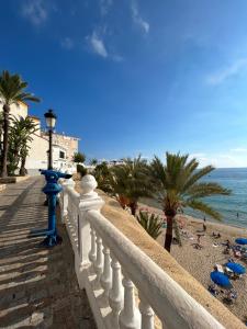 a white fence next to a beach with palm trees at Private apartment in the Old Town "Center&Beach" in Benidorm
