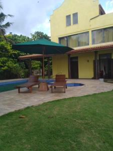 two benches and an umbrella in front of a building at Olivia Bungalow in Wattala